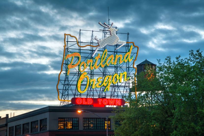 Neon sign reading "Portland Oregon" with a deer logo and "Old Town" at the bottom, set against a cloudy sky. Neon sign reading "Portland Oregon" with a deer logo and "Old Town" at the bottom, set against a cloudy sky.